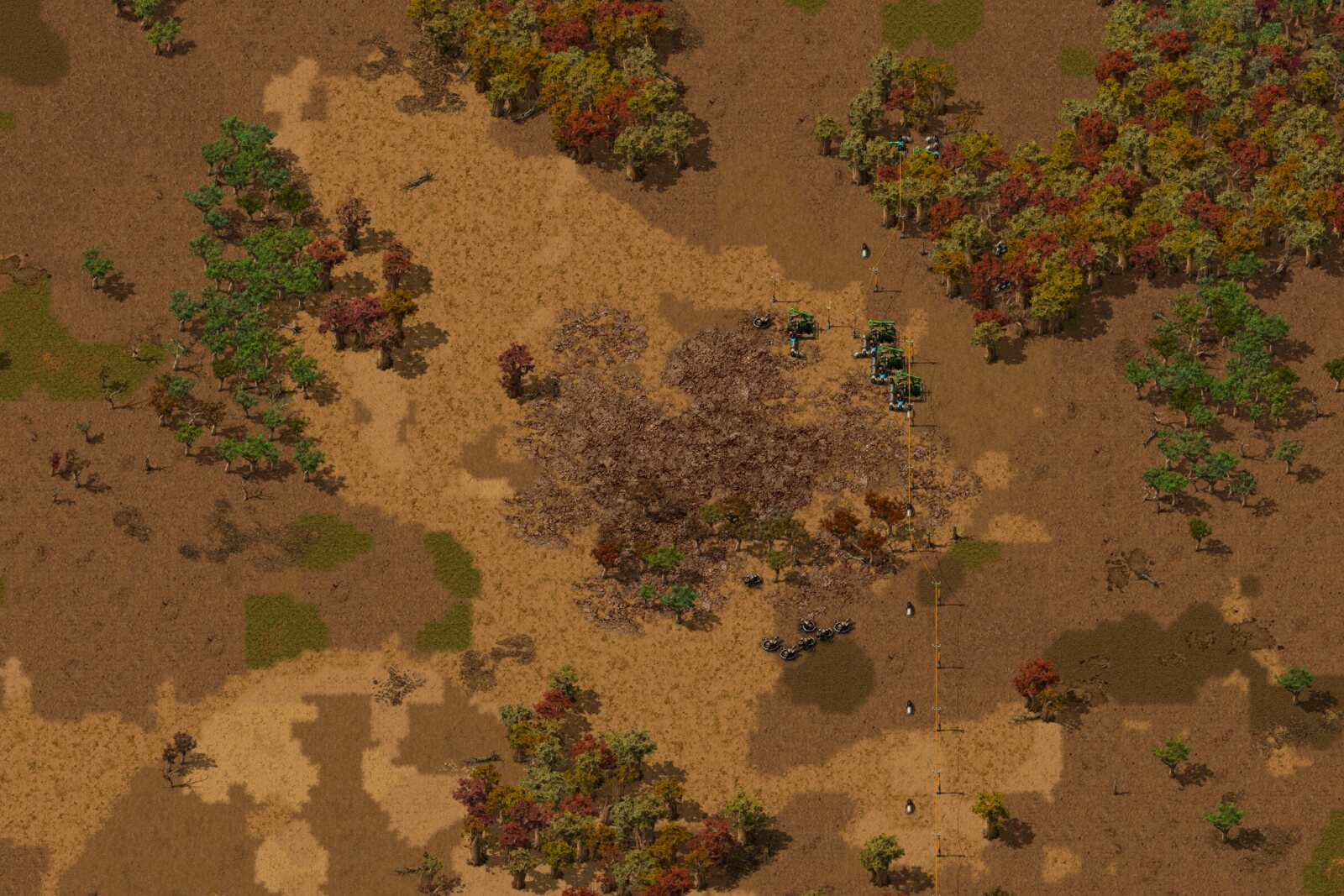 Overhead view of an oil field among autumn trees: a large dark patch of biter creep in the center, green pumpjacks being built at its upper right edge, and grey gun turrets just below it.